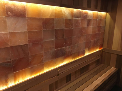 Pink Himalayan salt wall panels installed with warm backlighting above a sauna bench